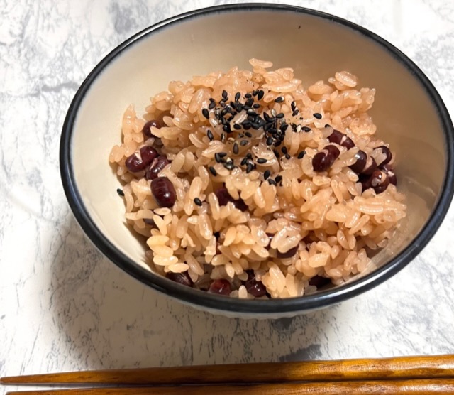 青い淵の白いお茶碗に入ってお赤飯と茶色のお箸